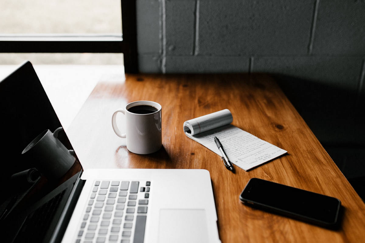 Laptop, coffee, and handwritten meeting notes on a desk